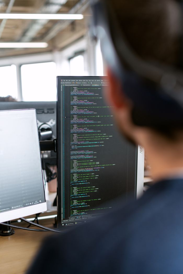 Services A male software engineer working on code in a modern office setting.